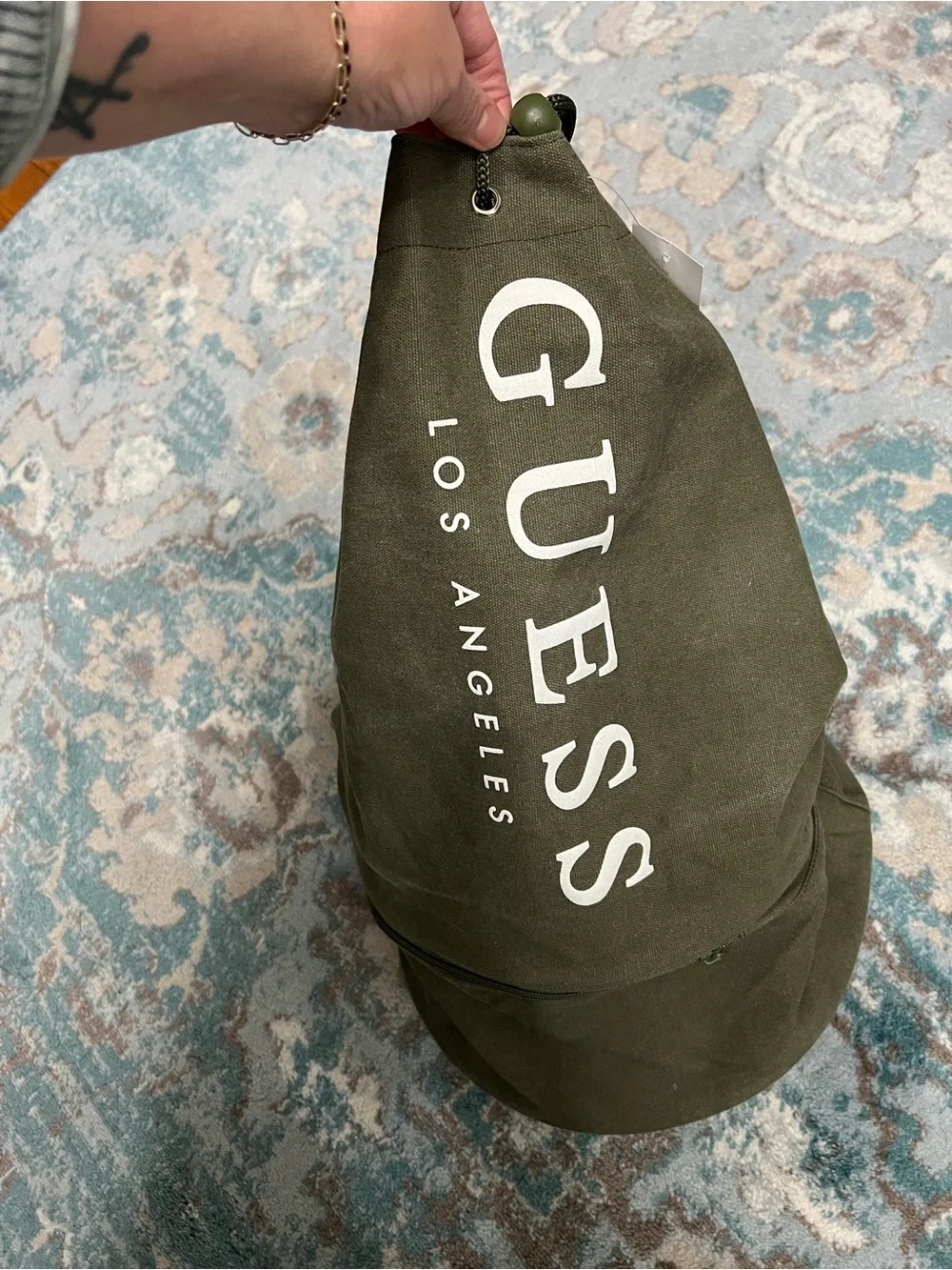 GUESS Olive Canvas Drawstring Sling Duffel Bag with zipper bottom.